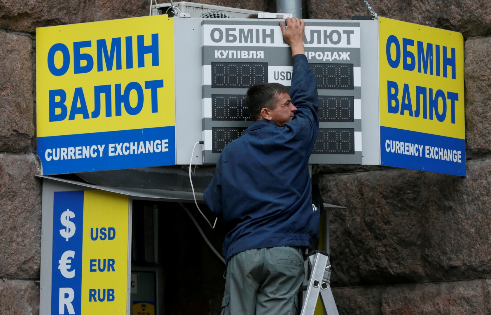 A man arranges a board outside a currency exchange office in central Kiev, Ukraine, August 12, 2016.  REUTERS/Valentyn Ogirenko - RTSMXH7