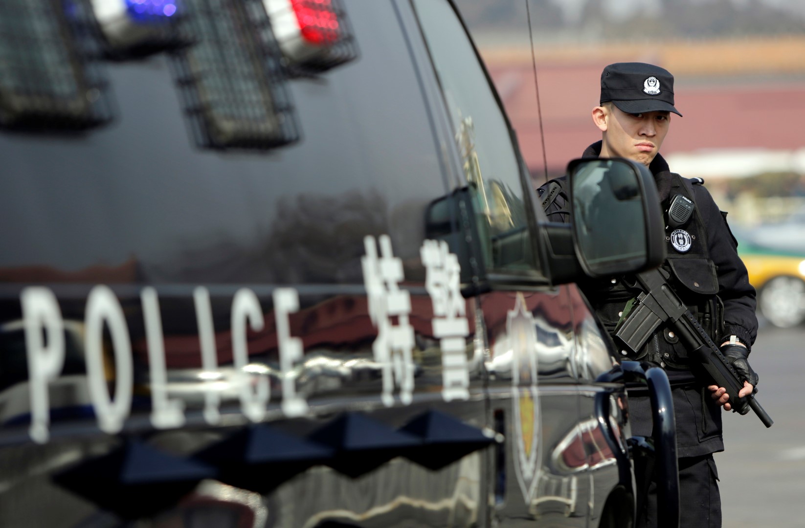 A policeman stands guard next to a vehicle of the Special Weapons and Tactics (SWAT) team on the Chang'an Avenue in front of the Tiananmen Square in Beijing ahead of the opening of the Chinese People's Political Consultative Conference (CPPCC), March 2, 2014. REUTERS/Jason Lee (CHINA - Tags: POLITICS MILITARY) - RTR3FW7J