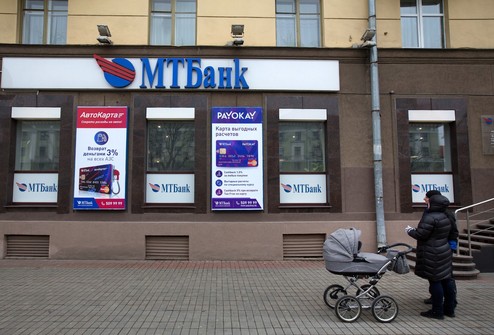 Pedestrians pause outside a branch of the Minsk Transit Bank CJSC, also known as MTBank, in Minsk, Belarus, on Wednesday, March 16, 2016. European Union governments scrapped sanctions on leaders of Belarus in an effort to pry the former Soviet republic out of the shadow of the Kremlin. Photographer: Andrey Rudakov/Bloomberg
