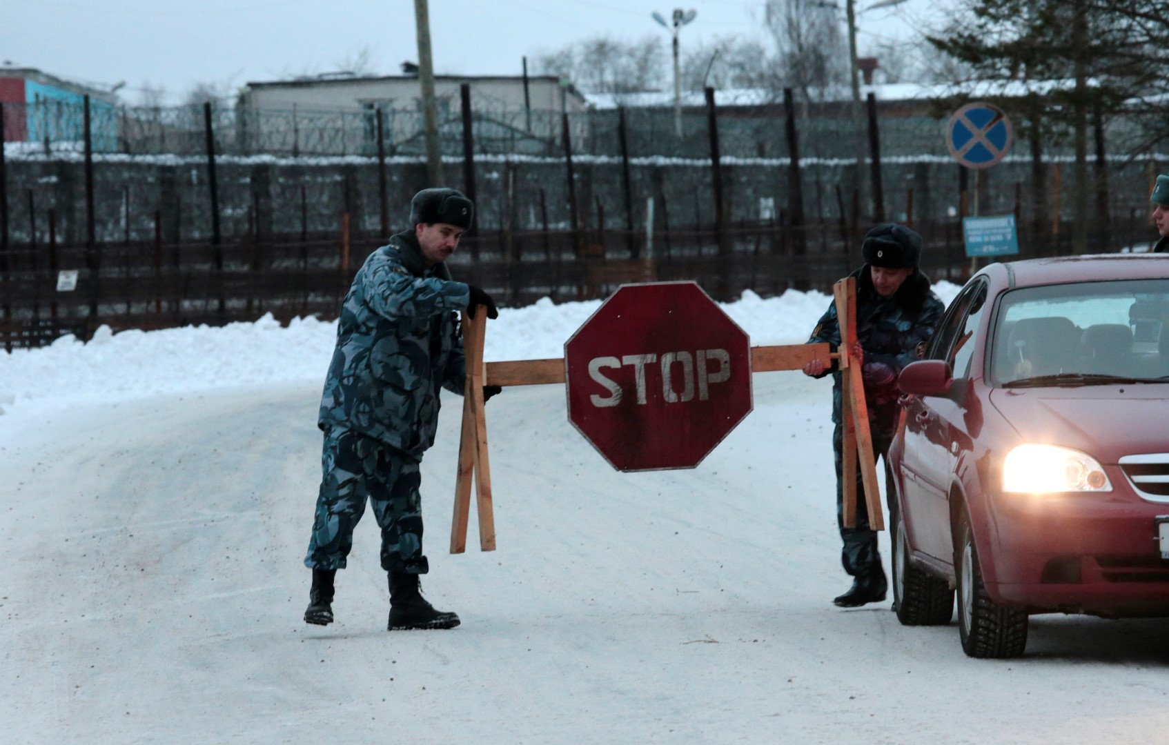 Police officers install a stop sign on a road leading to the Penal Colony No. 7 where Mikhail Khodorkovsky was held at the village of Segezha