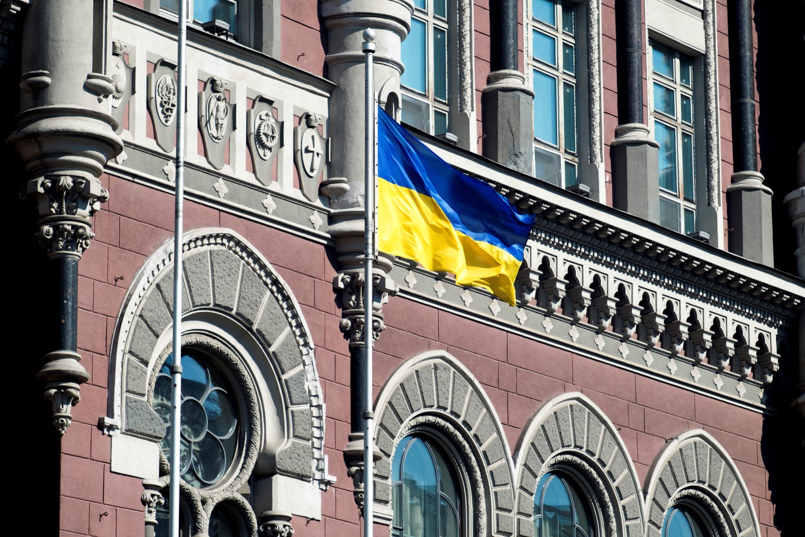 A Ukrainian national flag flies outside the Ukraine central bank in Kiev, Ukraine, on Friday, March 14, 2014. Ukraine's Eurobonds weakened and stocks headed for the worst week in seven on concern the conflict with Russia is intensifying two days before a referendum this weekend on the Crimean region's independence. Photographer: Vincent Mundy/Bloomberg