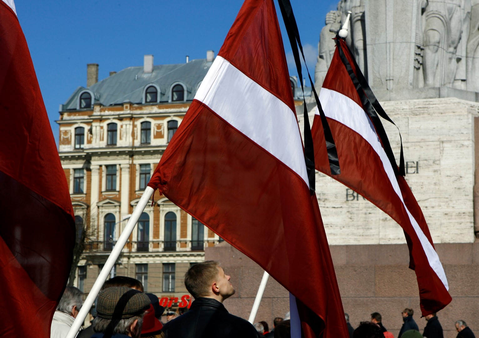 People hold Latvian flags in front of Freedom monument in Riga March 25, 2009, to commemorate the people who were deported to Siberia in 1949. The largest deportations took place in the Baltic states between March 25 and March 29, 1949, and more than 100,000 people were deported to remote areas of the USSR.  REUTERS/Ints Kalnins (LATVIA ANNIVERSARY SOCIETY) - GM1E53P1OT401