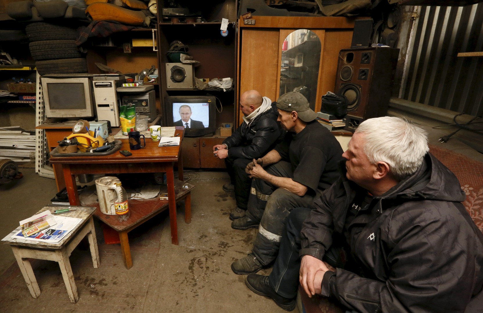 Workers watch a television broadcast of Russian President Vladimir Putin address to the Federal Assembly at an auto repair shop in the Siberian town of Divnogorsk near Krasnoyarsk, Russia, December 3, 2015. Putin used his annual state of the nation speech on Thursday to warn Turkey the Kremlin planned to adopt further sanctions against it to punish Ankara for shooting down a Russian warplane near the Syrian-Turkish border last week. REUTERS/Ilya Naymushin - GF20000083478