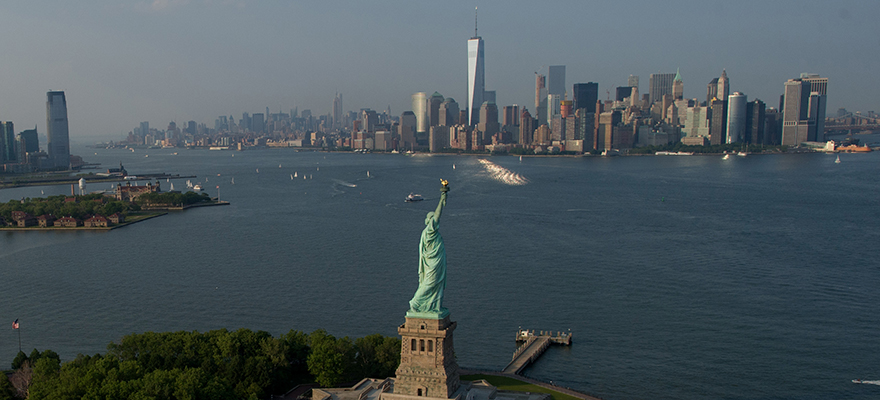 The Statue of Liberty stands ahead of One World Trade Center in the Manhattan skyline in this aerial photograph taken above New York, U.S., on Wednesday, June 10, 2015. U.S. stocks rallied and the dollar fell as the Federal Reserve signaled it will continue to support the economy. Photographer: Craig Warga/Bloomberg