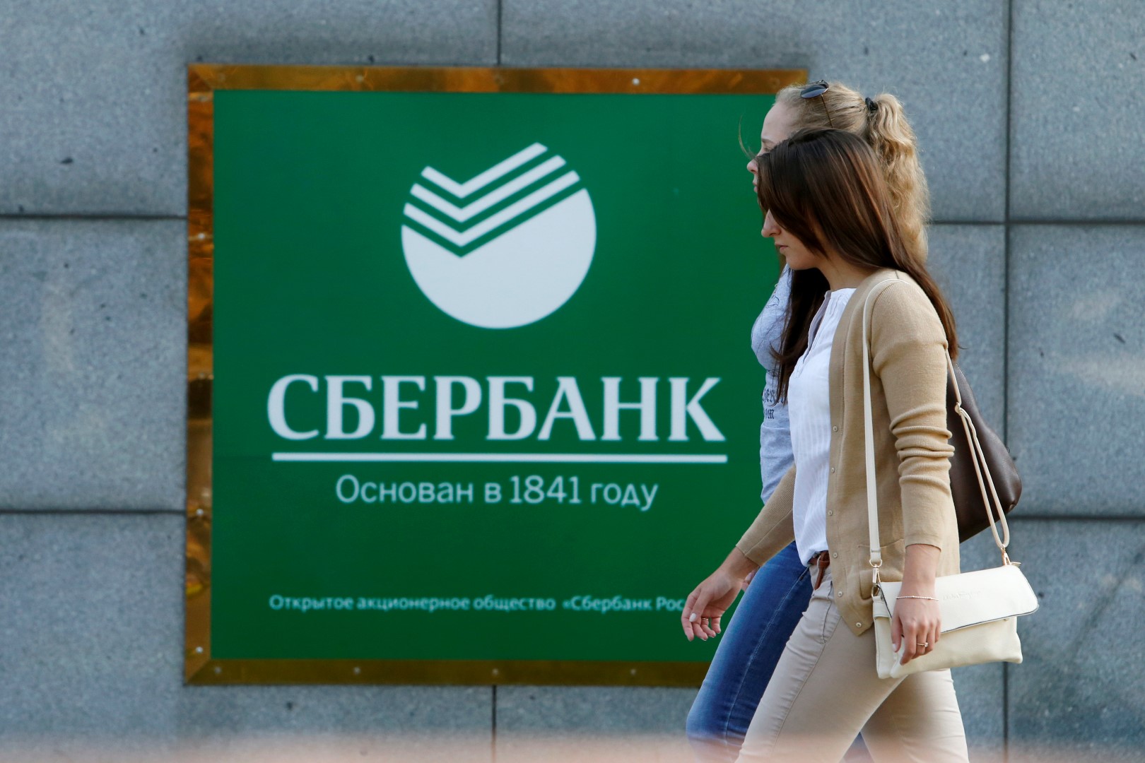Women walk past an office of Sberbank in Moscow September 12, 2014. The United States will take new steps to limit access of major Russian banks, including Sberbank, to U.S. debt and equity markets to punish Russia for its intervention in Ukraine, sources familiar with matter said. REUTERS/Sergei Karpukhin (RUSSIA  - Tags: BUSINESS POLITICS CIVIL UNREST CONFLICT) - GM1EA9C1CTZ01
