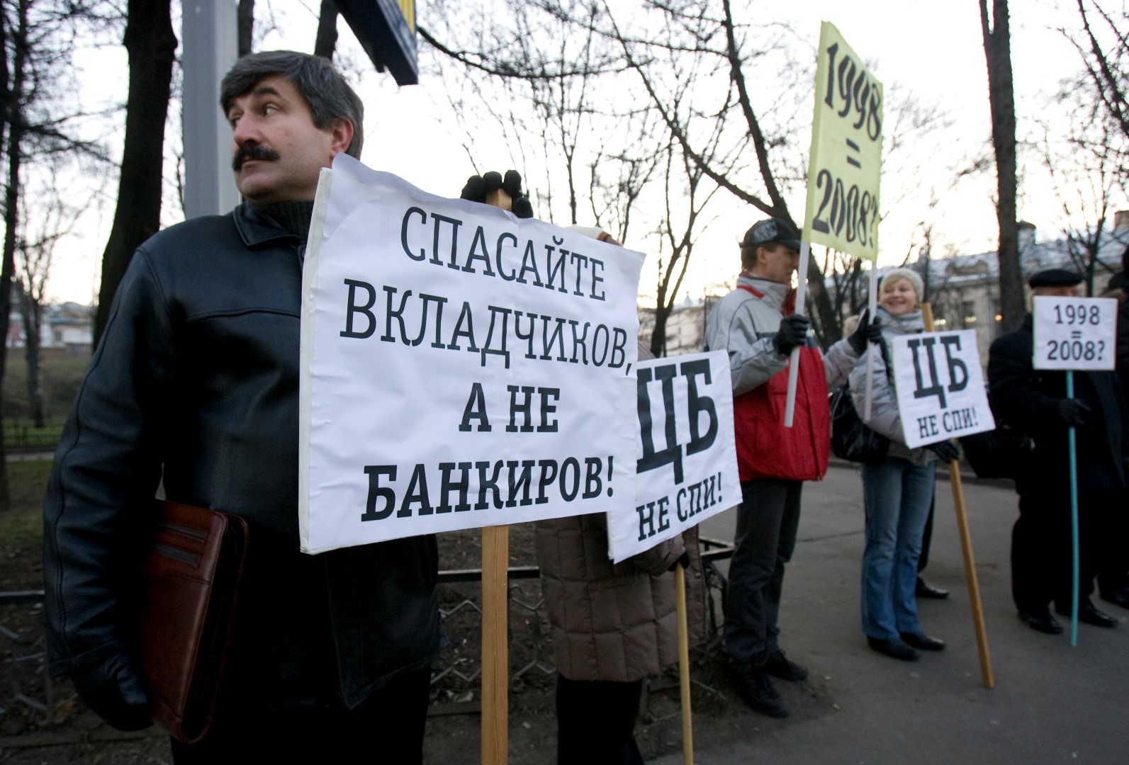 Investors of the bank Kapital Kredit stand with placards reading (L-R) "Save Investors, Not Bankers", "Central Bank, Wake Up!" and "1998 (Crisis) equals 2008" during a picket in front of the main building in Moscow, December 19, 2008. Bank investors gathered to claim their money from the bank. REUTERS/Sergei Karpukhin (RUSSIA) - GM1E4CJ1SDH01