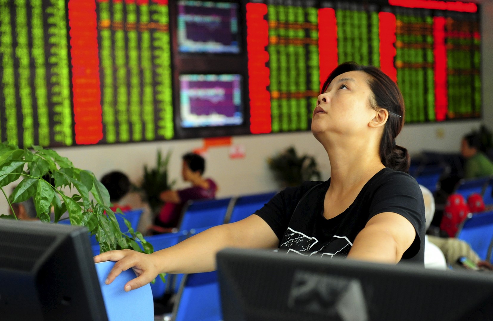 An investor looks up in front of an electronic board showing stock information at a brokerage house in Fuyang, Anhui province, China August 21, 2015. China stock markets tanked more than 4 percent on Friday, taking weekly losses for the main indexes to nearly 12 percent and casting doubt over Beijing's ability to prevent another bout of panic selling as the market neared collapse again. REUTERS/China Daily CHINA OUT. NO COMMERCIAL OR EDITORIAL SALES IN CHINA - GF10000178232